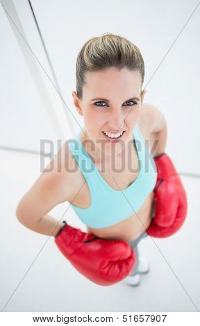 Fit woman wearing boxing gloves looking at camera