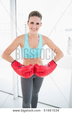 Competitive woman wearing red boxing gloves in bright fitness studio