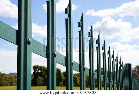 Section Closeup Of Green Palisade Security Fence Against Blue Sky