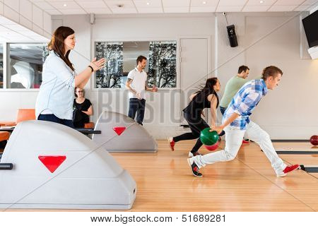 Side view of young friends bowling together in club