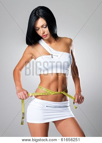 Slim woman and measure tape around her body - a studio shot