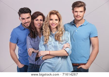 blonde woman leading her happy team, smiling on grey background