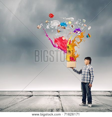 Young boy splashing colorful paint from bucket