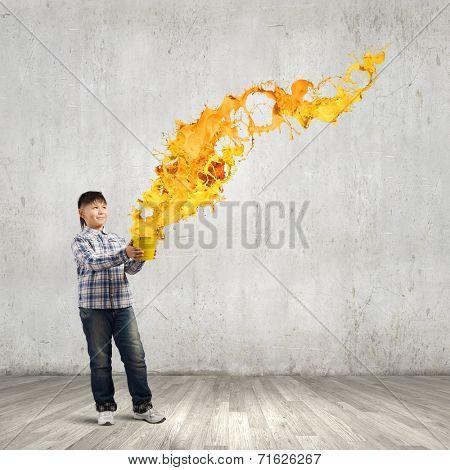 Young boy splashing colorful paint from bucket