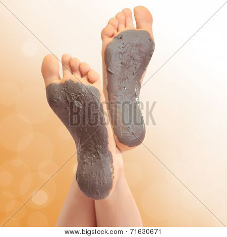 Woman foots with cosmetic clay on bright background