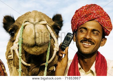 Asian man and camel in the desert with communication, Rajasthan, India.