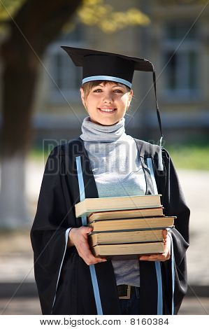 Mladá samice absolvent s hromadou knih