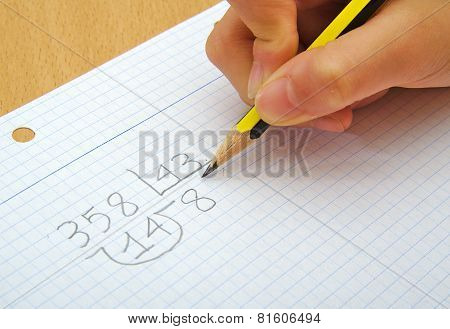 Closeup on the hands of a child doing maths. Division. School concept.