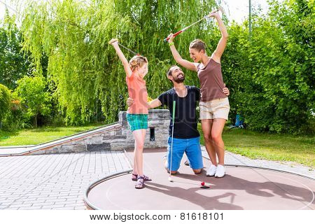 Family playing miniature golf outdoors