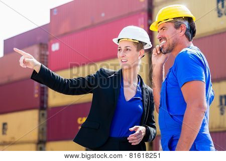 Freight shipping at container terminal of port, worker and manager discussing shipments