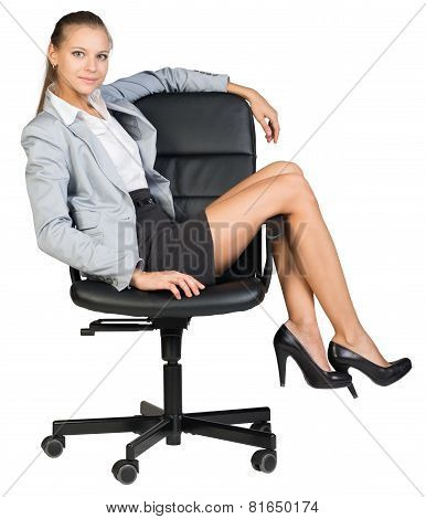 Businesswoman on office chair with her legs over armrest