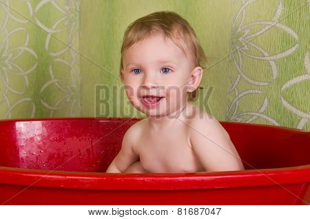 Beautiful little blond girl sitting in the bathroom and chew toys