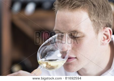 Man Smelling A Glass Of White Wine.