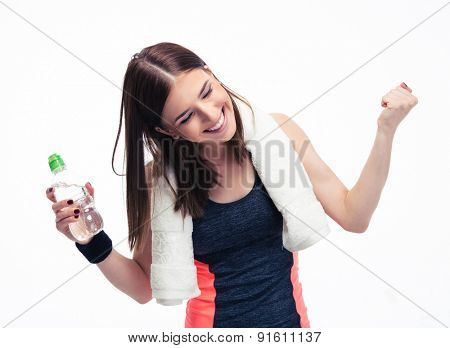 Happy fitness woman with towe and bottle of water celebrating her victory isolated on a white background. Looking at camera