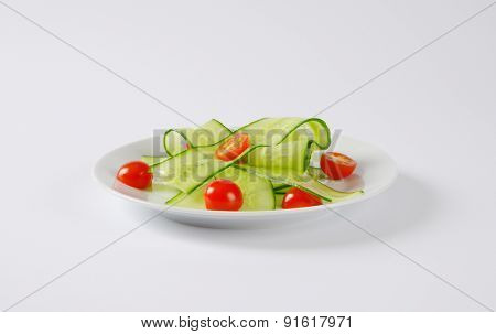 salad with thin slices of cucumber and halved cherry tomatoes, served on the round plate