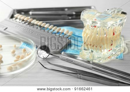 Fake teeth, prosthesis and dental instruments on table background