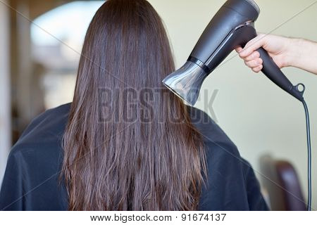 beauty, haircare, blow-dry, hairstyle and people concept - stylist hand with fan dries woman hair at salon