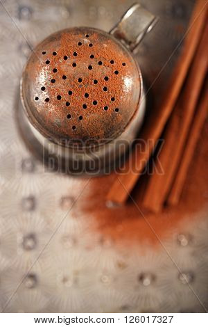 vintage sifter with cocoa powder and cinnamon sticks