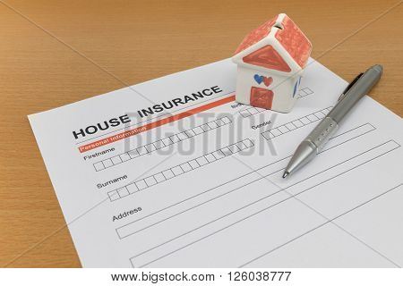 House Insurance application form with model house and pen