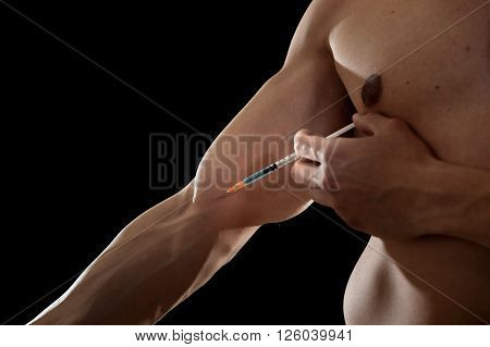 young body building sportsman using steroids for increasing sport and athletic performance injecting syringe in his arm in sport cheat doping and illegal use of hormones