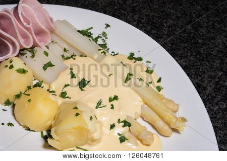 cooked white asparagus with potatoes parslay and ham