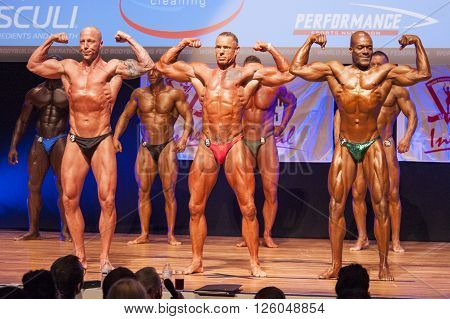 MAASTRICHT THE NETHERLANDS - OCTOBER 25 2015: Male bodybuilders flex their muscles and show their best physique in a front double biceps pose on stage at the World Grandprix Bodybuilding and Fitness of the WBBF-WFF