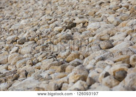 White yellow brown big and small natural stones levee at Dead Sea background