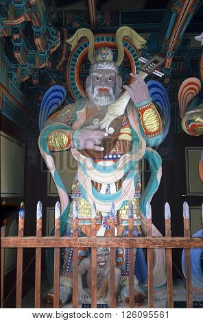 GYEONGJU CITY, NORTH GYEONGSANG PROVINCE / KOREA - CIRCA 1987: A large sculpture of a bearded man playing a lute stands behind a picket fence inside the Bulguksa Buddhist Temple.