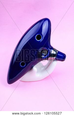Blue Ceramic Ocarina with stand on pink background