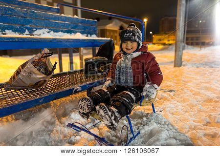 boy sledding in the evening cold winter