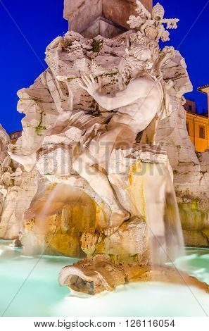 Illuminated at night the fontana del Moro (the Moor Fountain) on Piazza Navona on the Sant'Agnese in Agone church background, Rome, Italy