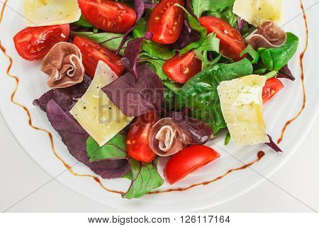 Fresh Mediterranean salad with prosciutto, parmesan cheese and vegetables.