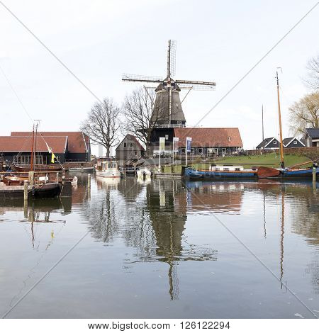 harderwijk, netherlands, 1 april 2016: old harbor in dutch town of harderwijk with windmill De Hoop in the background