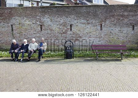 harderwijk, netherlands, 1 april 2016: four elderly people sit on bench in the old dutch town of harderwijk
