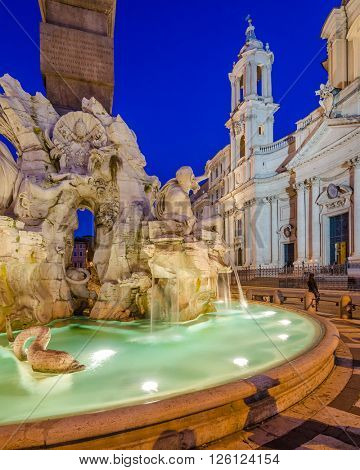 Illuminated at night the fontana del Moro (the Moor Fountain) on Piazza Navona on the Sant'Agnese in Agone church background, Rome, Italy