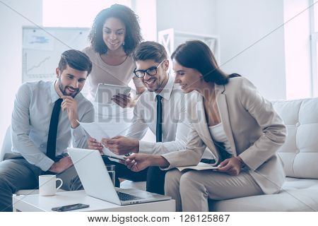 We have great results! Young beautiful woman pointing at her laptop with smile while sitting on the couch at office with her coworkers
** Note: Shallow depth of field