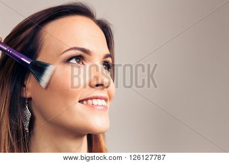 Makeup artist applies skintone on client face. Beautiful woman smiling face. Perfect makeup. Skincare foundation. The process of working professional makeup.