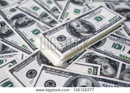 Close-up of a stack of one hundred dollar bills on a background of money. Fake money. Shallow depth of field. Selective focus.