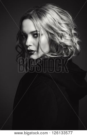 Black-and-white portrait of a blonde young woman with dark dramatic make-up. 