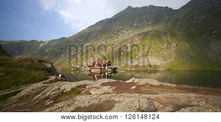 BALEA LAKE, ROMANIA - JULIY 22, 2015: Beautiful view of Balea Lake cottage on Fagaras Mountains, Carpathian, Romania. The image of the chalet is reflected in the lake.