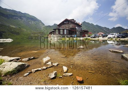 BALEA LAKE, ROMANIA - JULIY 22, 2015: Beautiful view of Balea Lake cottage on Fagaras Mountains, Carpathian, Romania. The image of the chalet is reflected in the lake.