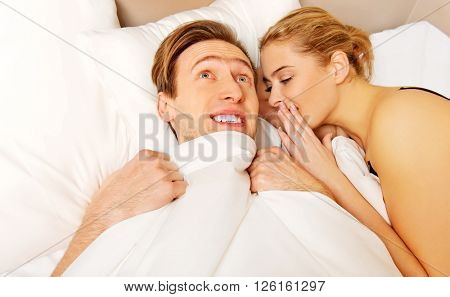 Woman whispering to her husband and he laughting