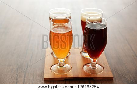 Glasses with different sorts of craft beer on wooden tray