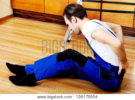 Hadyman sitting next to the ledder on the floor with back ache