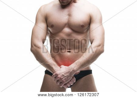 Man with pain in the prostate. Muscular male body. Handsome bodybuilder posing in studio. Isolated on white background with red dot. Middle part of the body