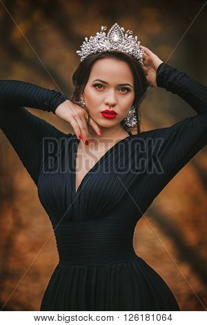 Beautiful woman model in jewelry crown in an autumn garden