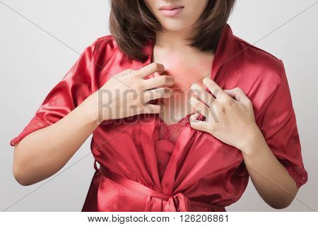 Woman scratching her itchy chest, on white background