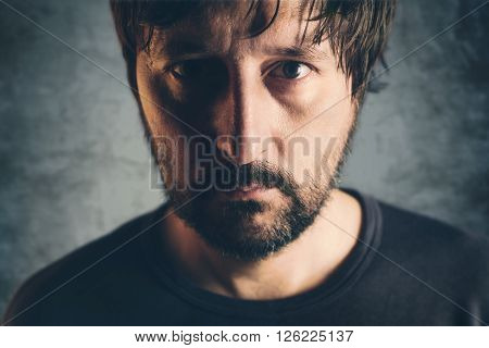 Dramatic low key portrait of adult male headshot of sad lonely unshaven person selective focus