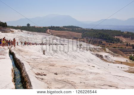 PAMUKKALE TURKEY - September 13 2015: Tourists regard the travertines with pools and terraces at Pamukkale. Pamukkale is included in the UNESCO World Heritage List.