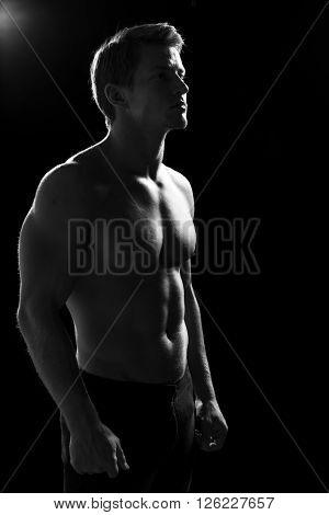 Strong young athletic guy in contour light